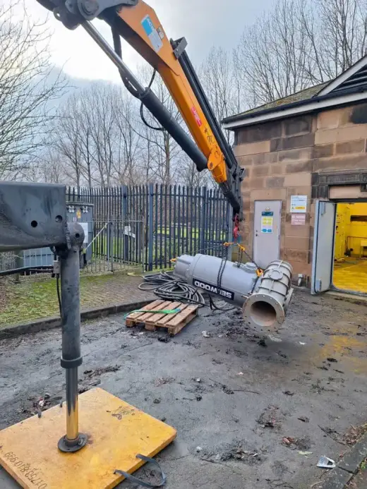 HIAB crane lifting industrial ducting out of a stone building