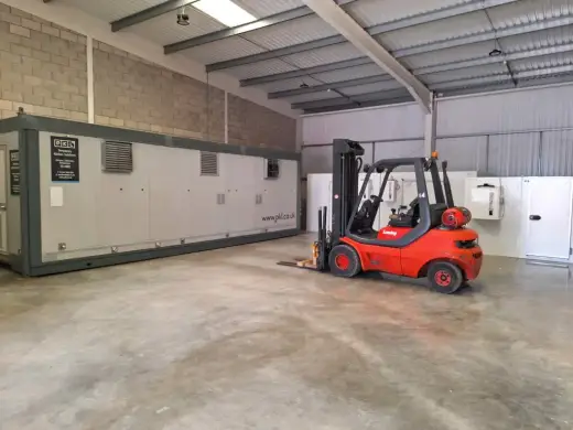 Forklift moving a portable welfare cabin inside a warehouse