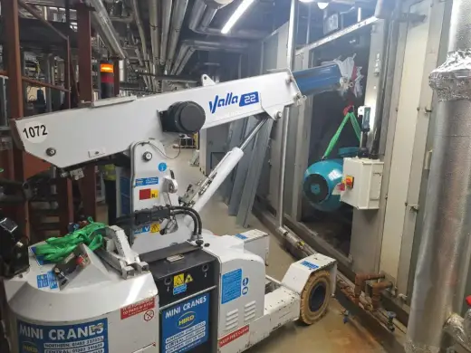 Compact pick-and-carry crane lifting a motor inside a plant room