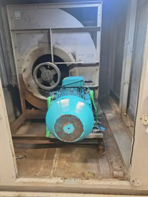 Electric motor inside an industrial fan housing awaiting removal