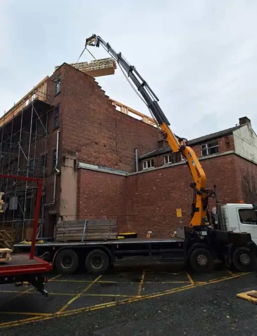 HIAB crane lorry working beside a partly demolished brick building