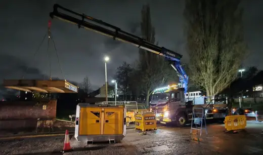 HIAB crane lifting a portable generator at night