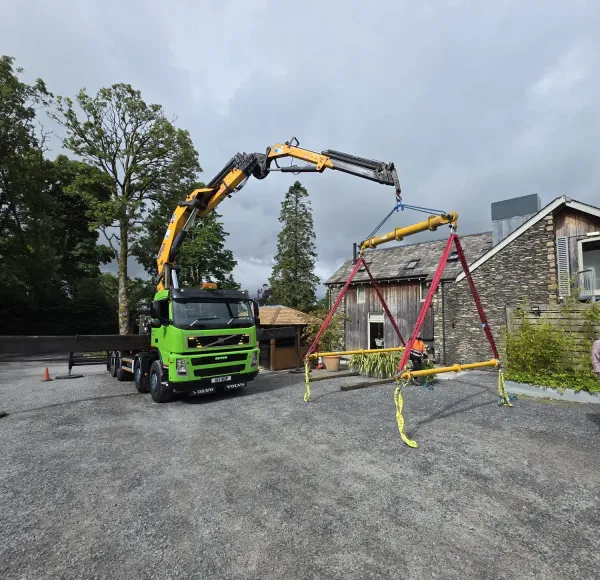 HIAB crane lifting over a garden with mature trees