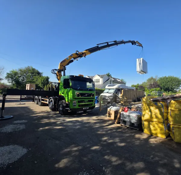 HIAB crane lifting a white unit over a garden fence