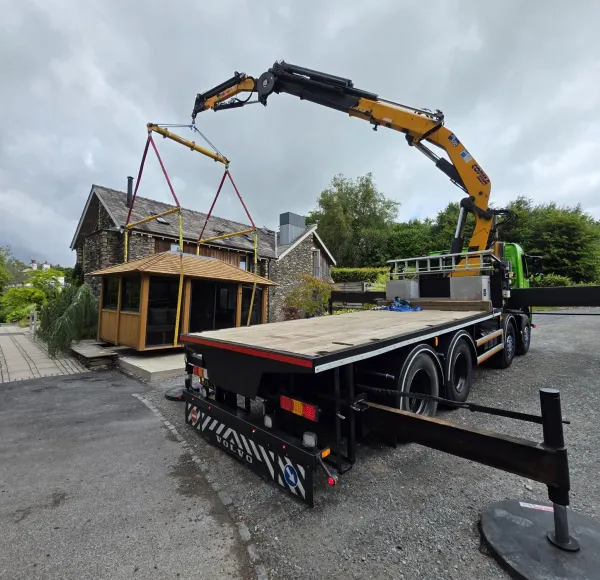 HIAB lorry with outriggers down lifting a summerhouse