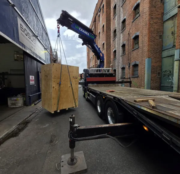 HIAB lorry lifting wooden crates beside a brick building