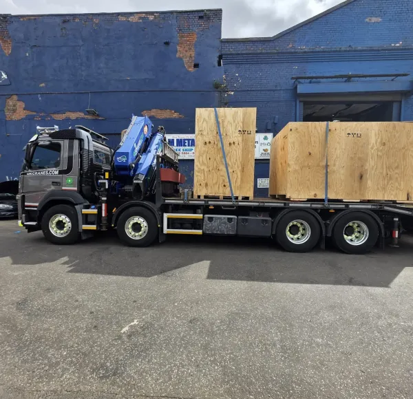 HIAB lorry loaded with wooden crates beside a blue building