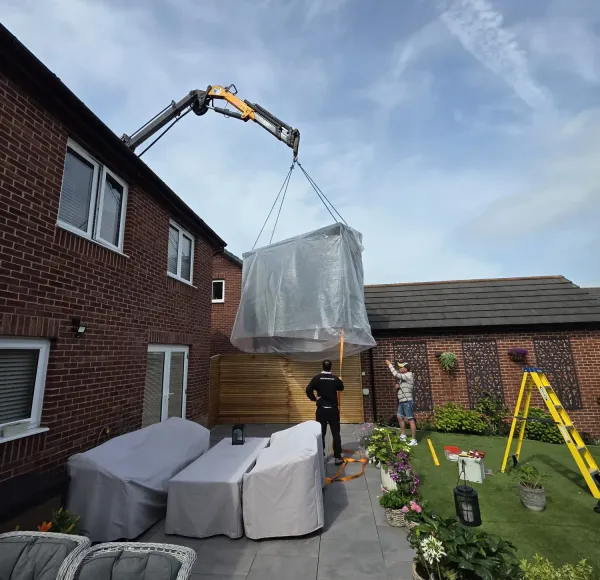 HIAB crane lifting a hot tub into a back garden