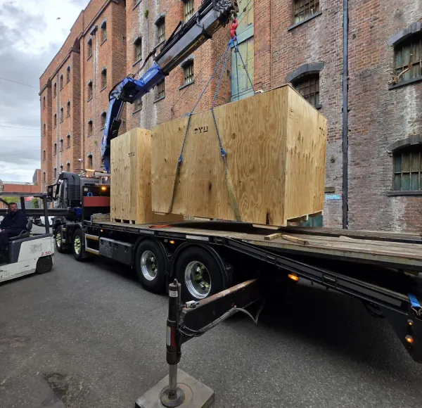 HIAB lorry unloading crates beside a mill building