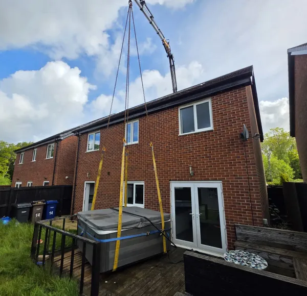 HIAB crane lifting a load behind a house