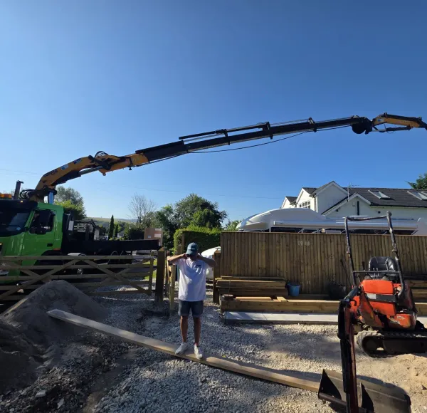 HIAB crane lifting materials into a back garden