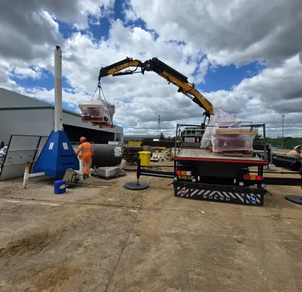 HIAB crane lifting red machinery at an industrial site