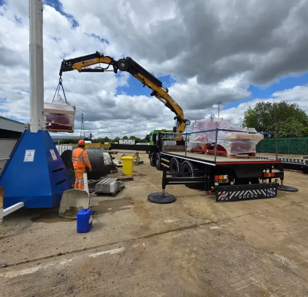 Operatives positioning red machinery lifted by a HIAB crane