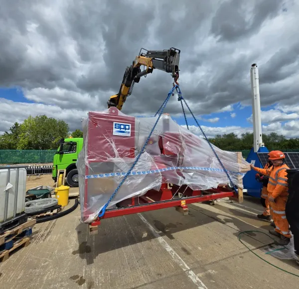 Close-up of red machinery suspended from a HIAB crane