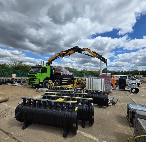 HIAB lorry lifting black plastic tanks on site