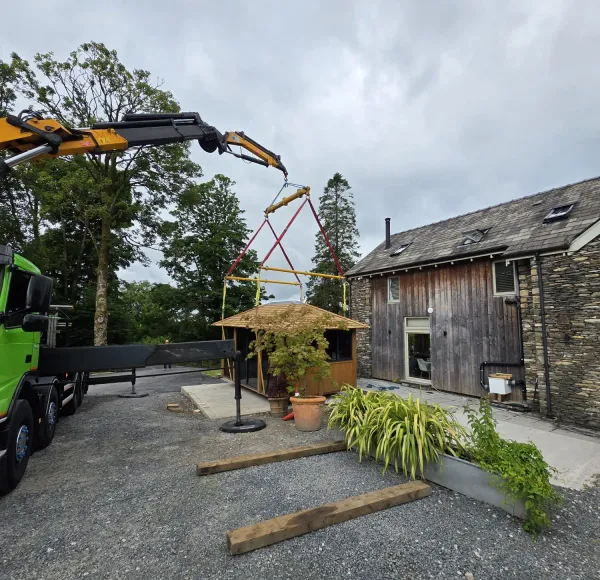 HIAB crane lifting a timber garden building