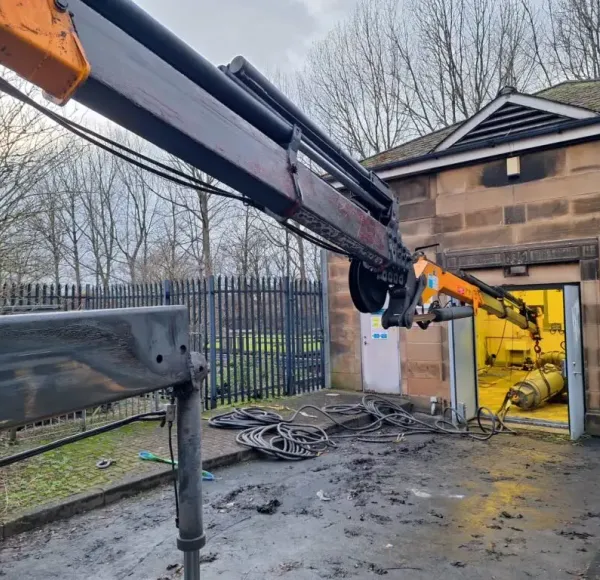 HIAB crane lifting machinery out of a building doorway