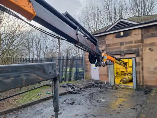 HIAB crane lifting machinery out of a building doorway