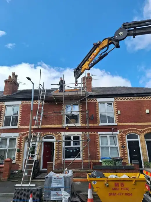 HIAB crane lifting at a terraced house with scaffolding