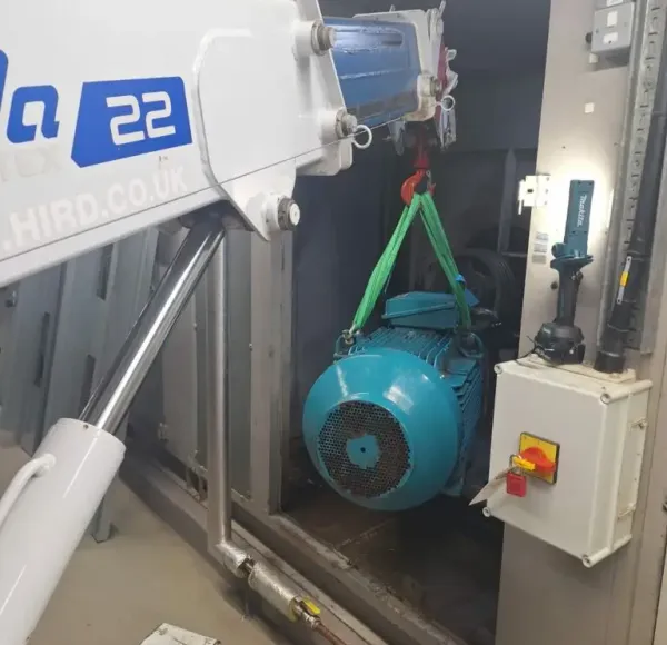 Compact crane lifting an electric motor inside a plant room
