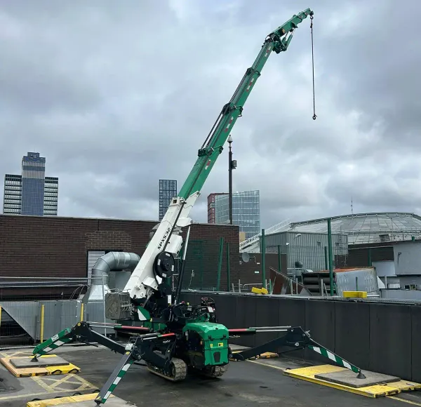 Green spider crane on outrigger pads on a rooftop