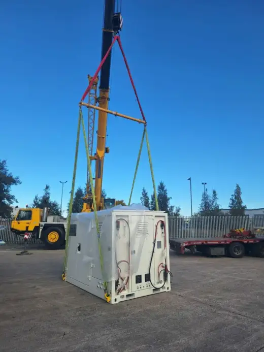 Yellow mobile crane lifting a white plant unit