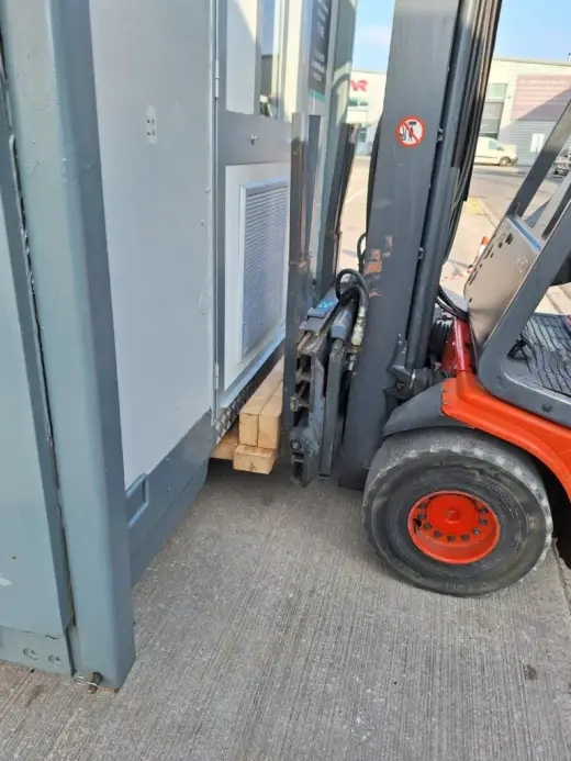 Forklift lifting a portable cabin inside a unit