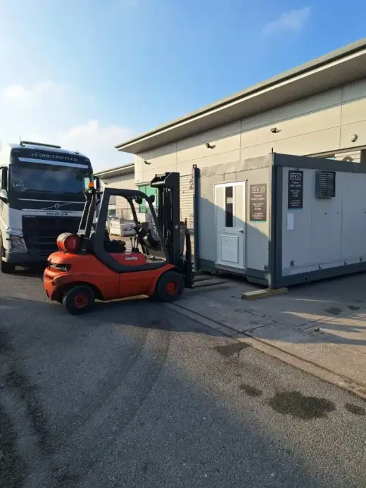 Forklift moving a portable cabin outside an industrial unit
