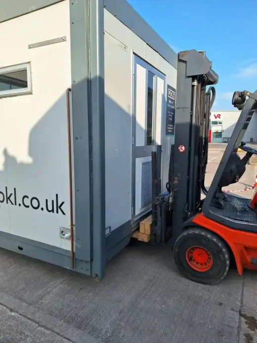 Forklift moving a portable welfare cabin
