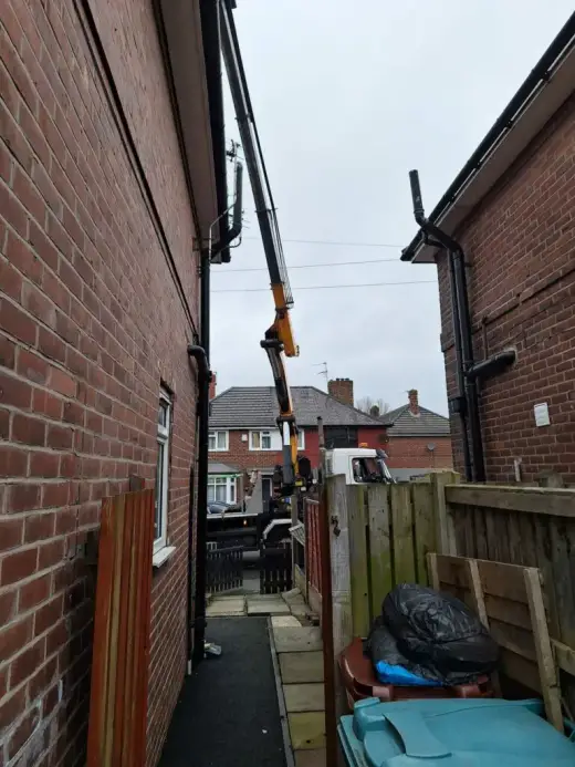 HIAB crane lifting in a narrow alley between houses