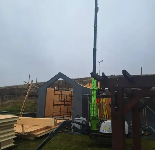 Spider crane beside a timber cabin on a hillside site