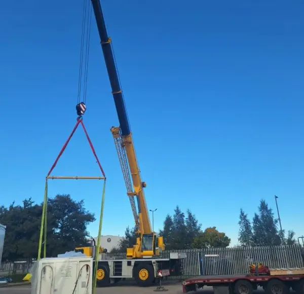 Yellow mobile crane lifting a load against a blue sky