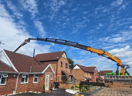 HIAB crane with a long boom lifting over bungalows