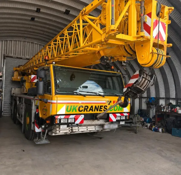 Yellow mobile crane parked inside an arched depot building