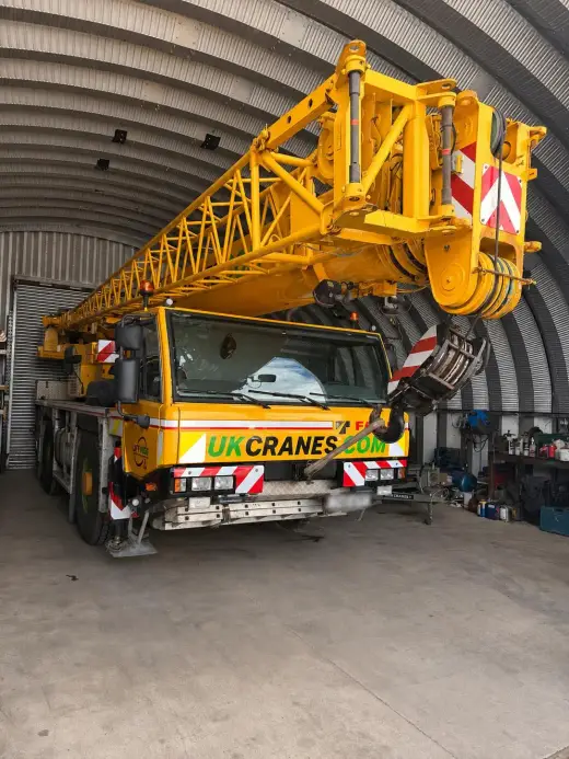 Yellow mobile crane parked inside an arched depot building