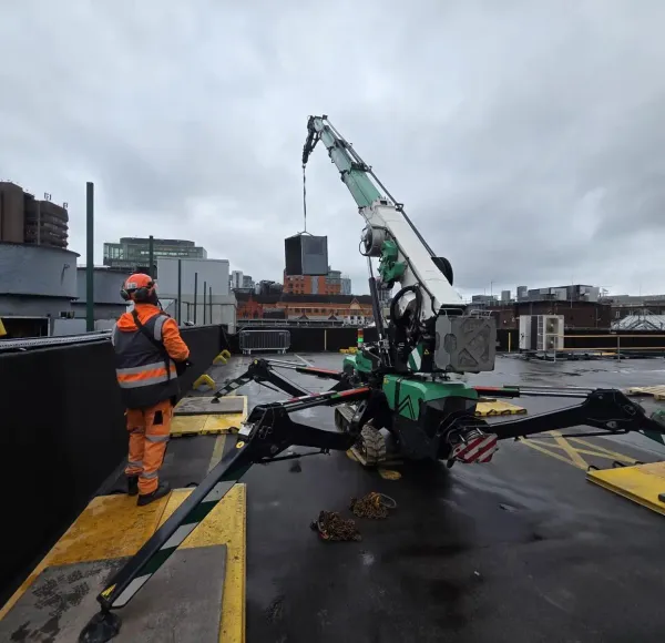 Spider crane lifting on a rooftop with an operative in hi-vis